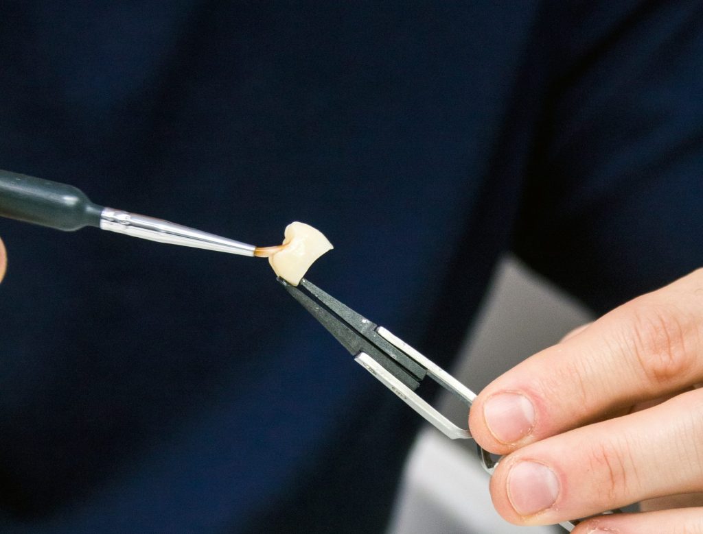 a person is holding a paintbrush and painting a piece of art